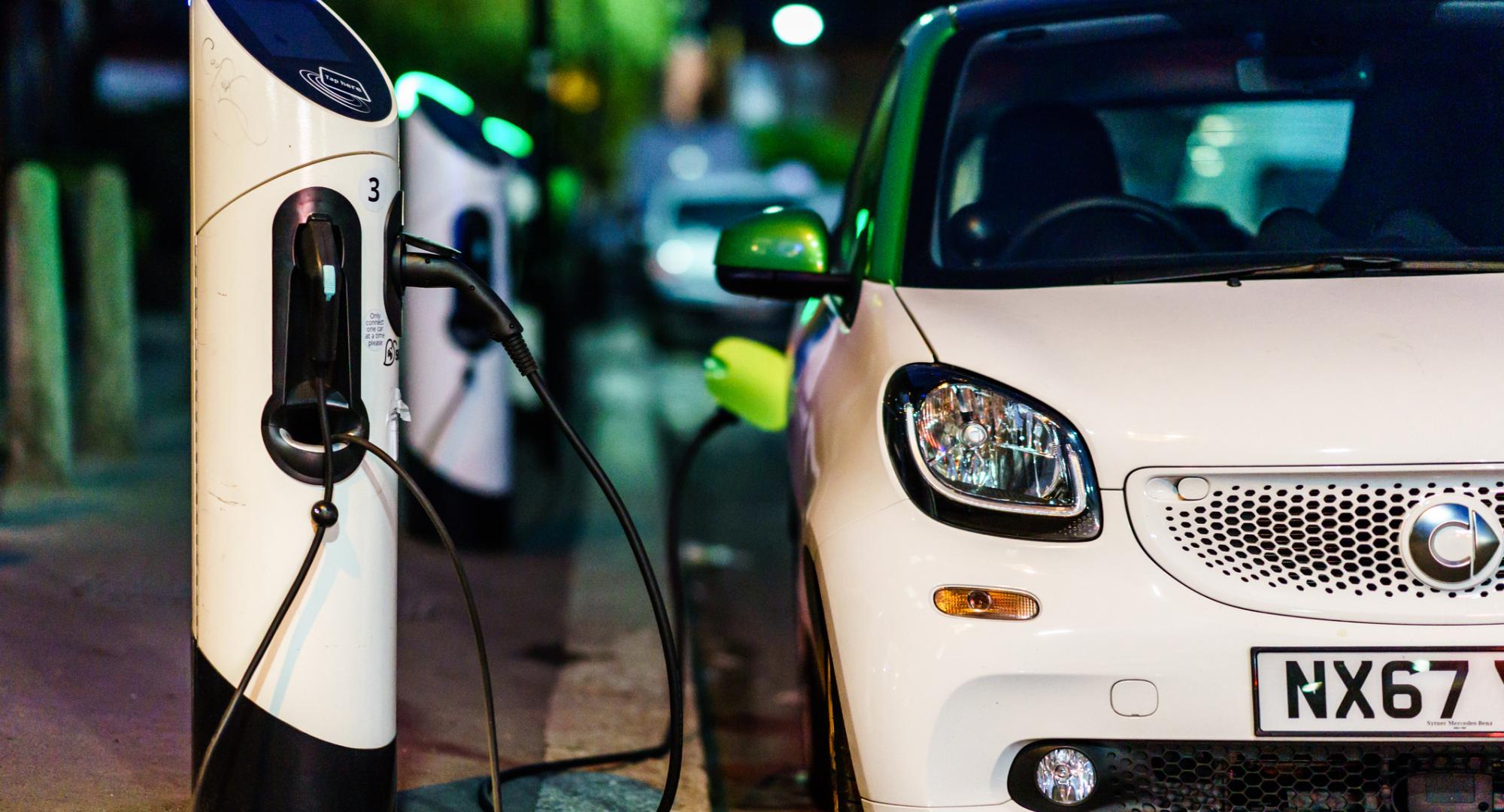 Car plugged into EV charge point on the road side