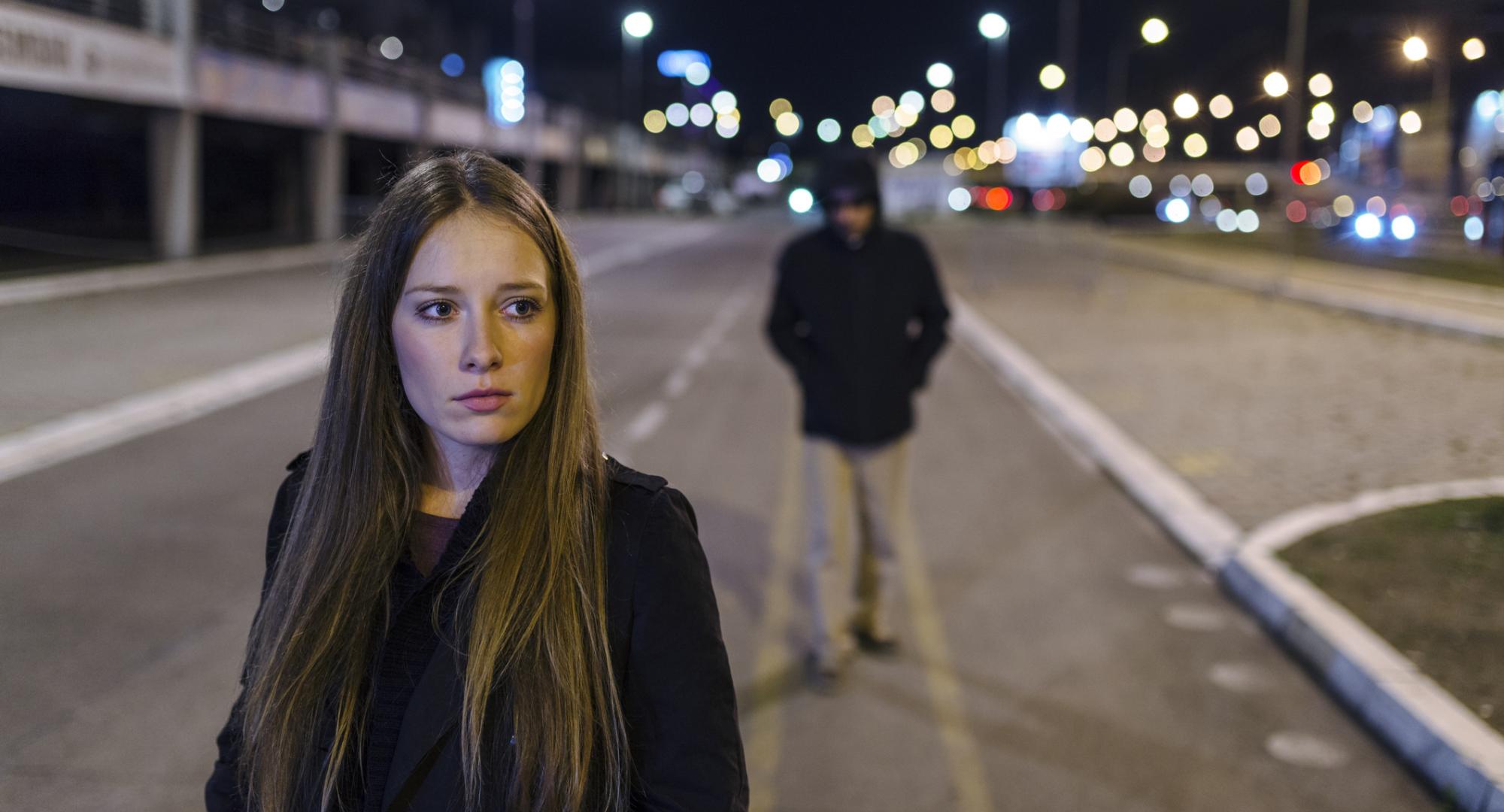 Woman walking alone with man walking behind