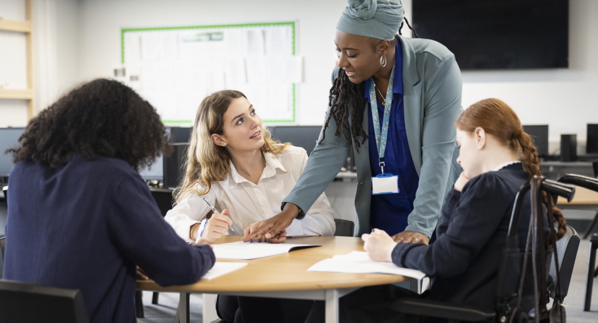 A female teacher helps students with their work