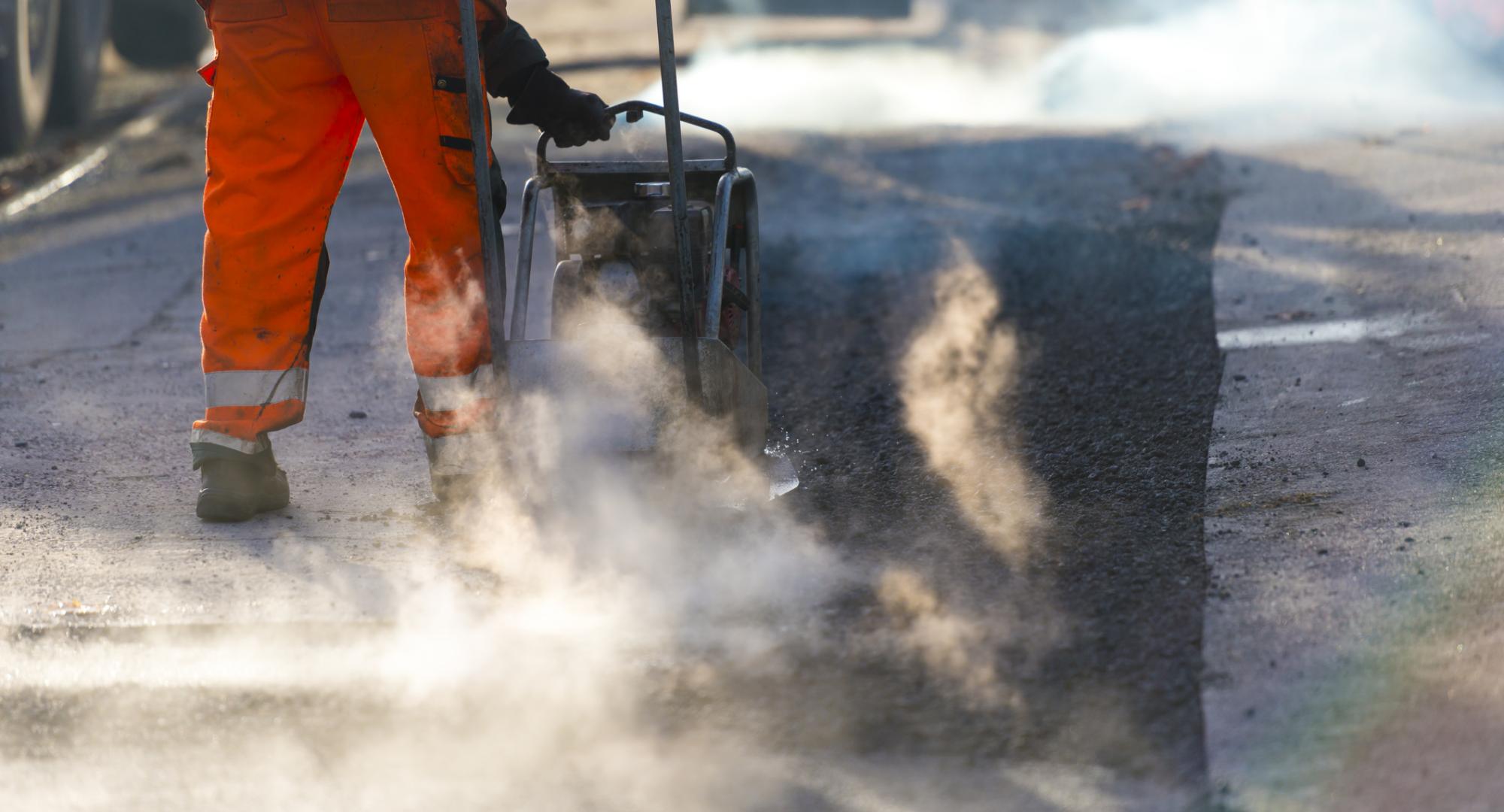 Road maintenance worker resurfacing tarmac