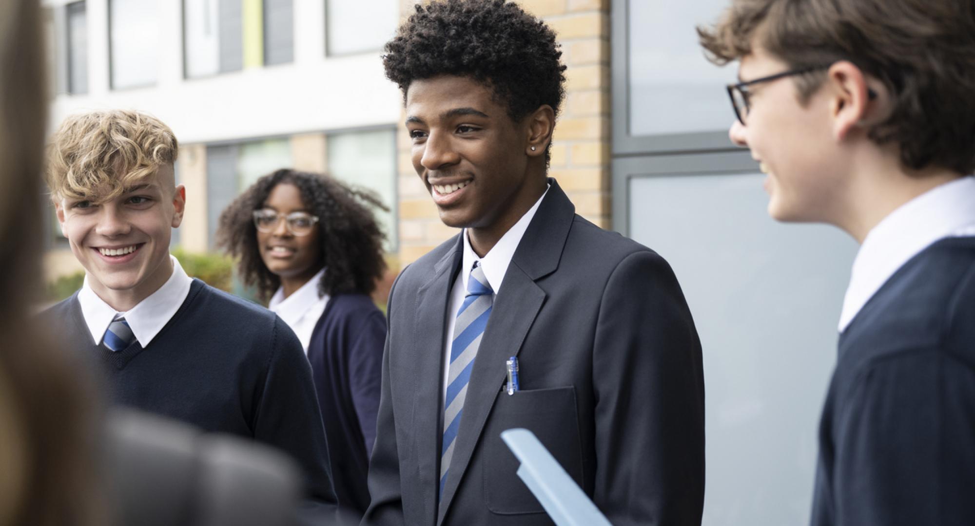 A diverse set of secondary school pupils stood outside a classroom 