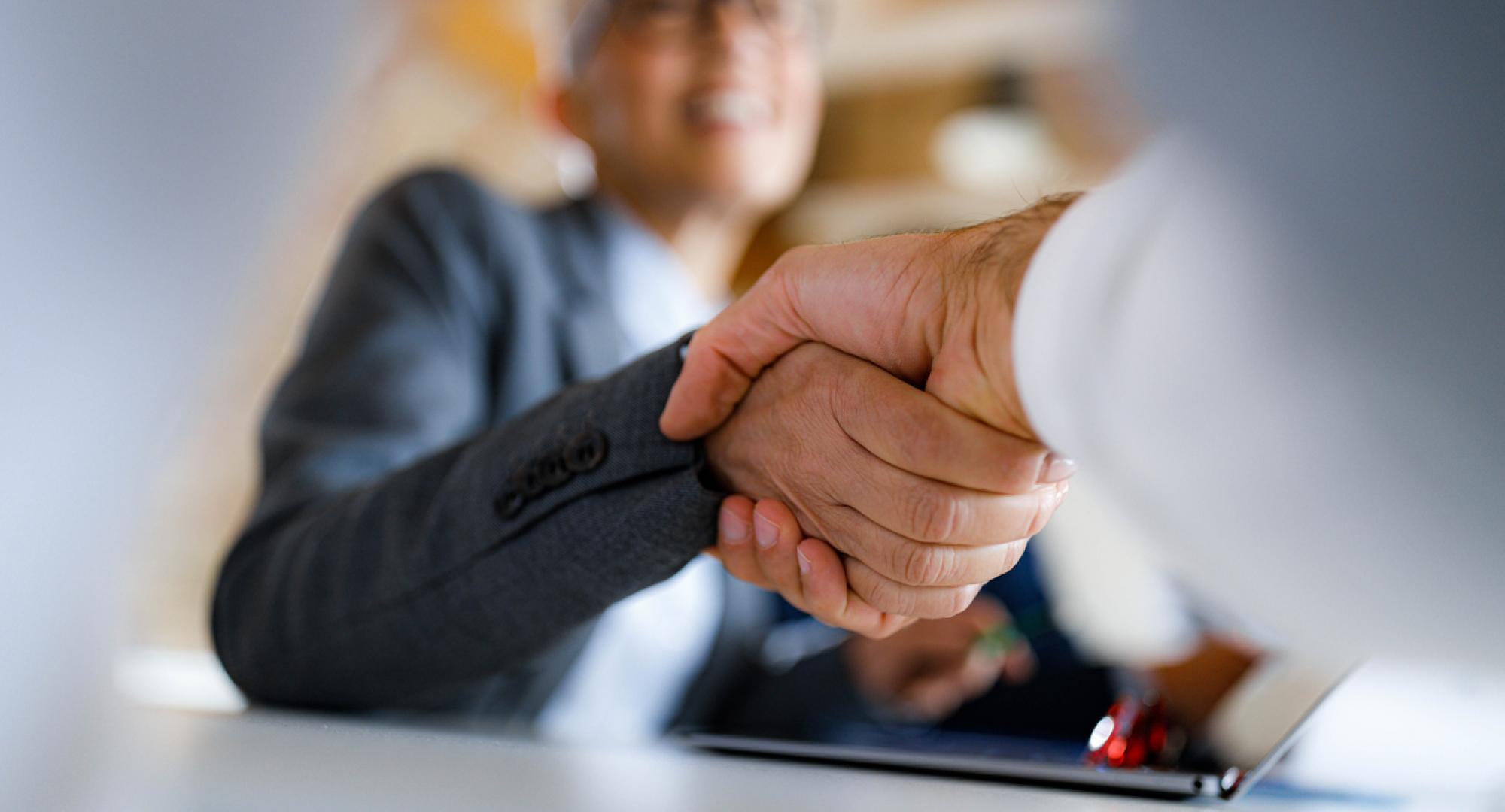 Close up shot of two people shaking hands in a business environment