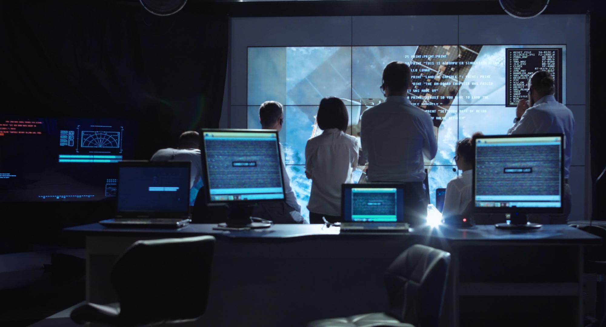 A group of people gather round a big screen whilst working on a digital project