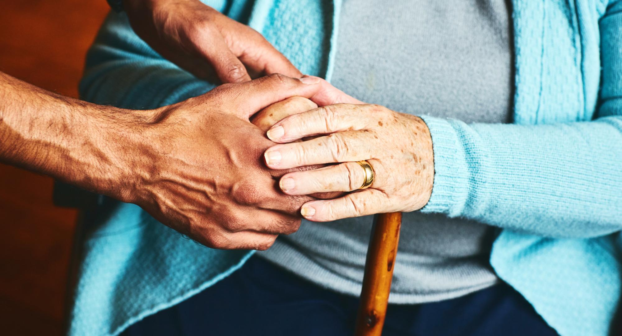 A carer holds hands with an older person