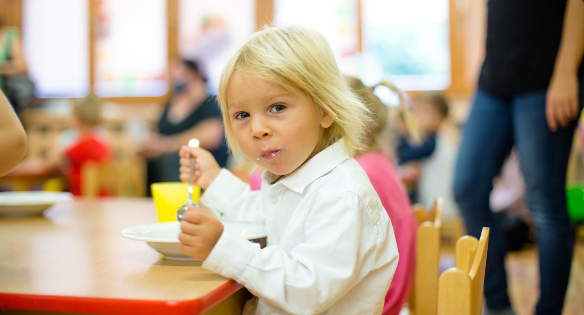 A child sits at school and eats lunch