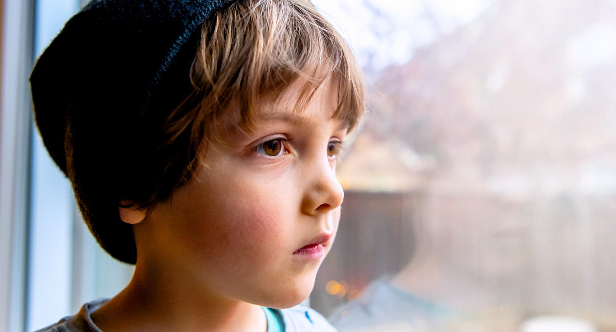 Pensive looking child looks out of a window