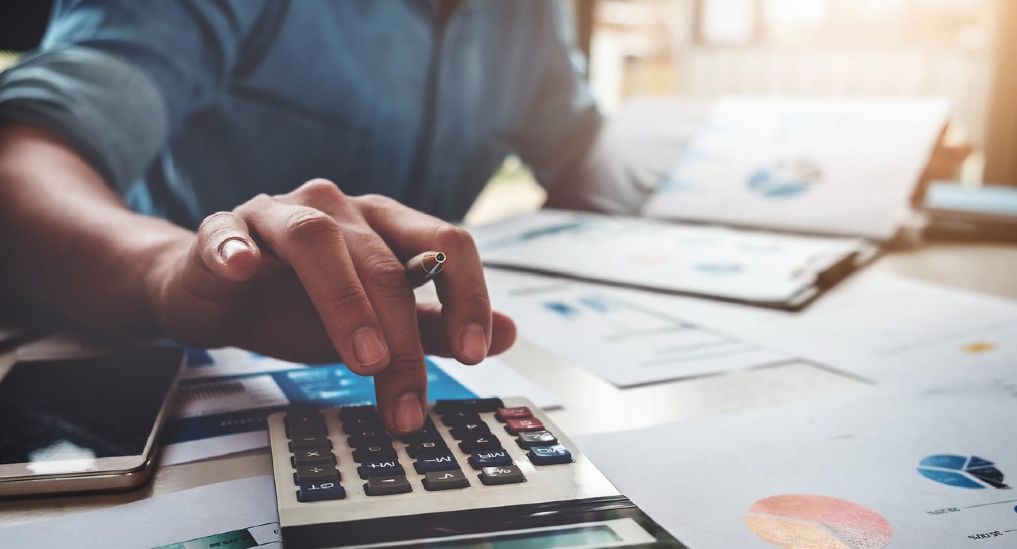 An unidentifiable man working out a budget with a calculator