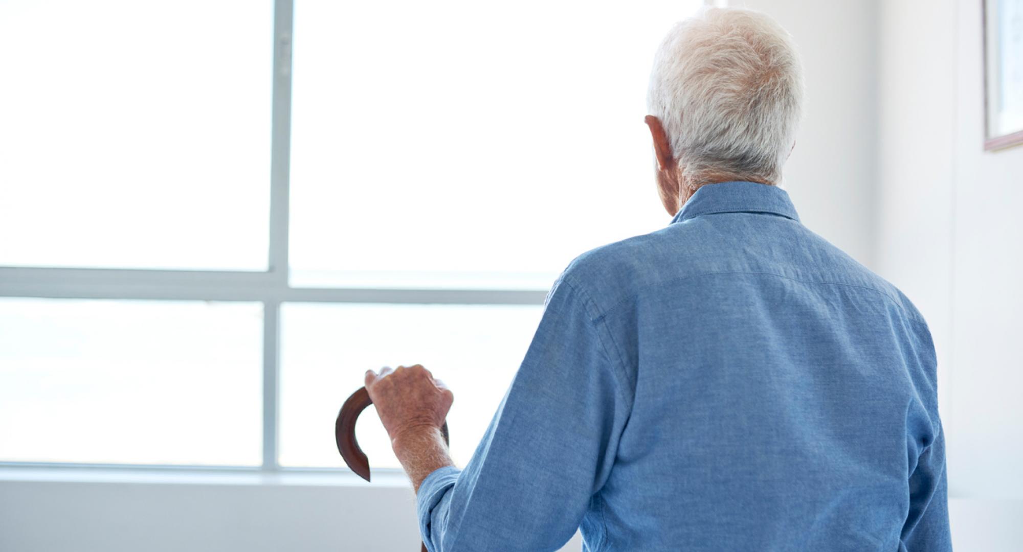 Old man with dementia looks out of a window.