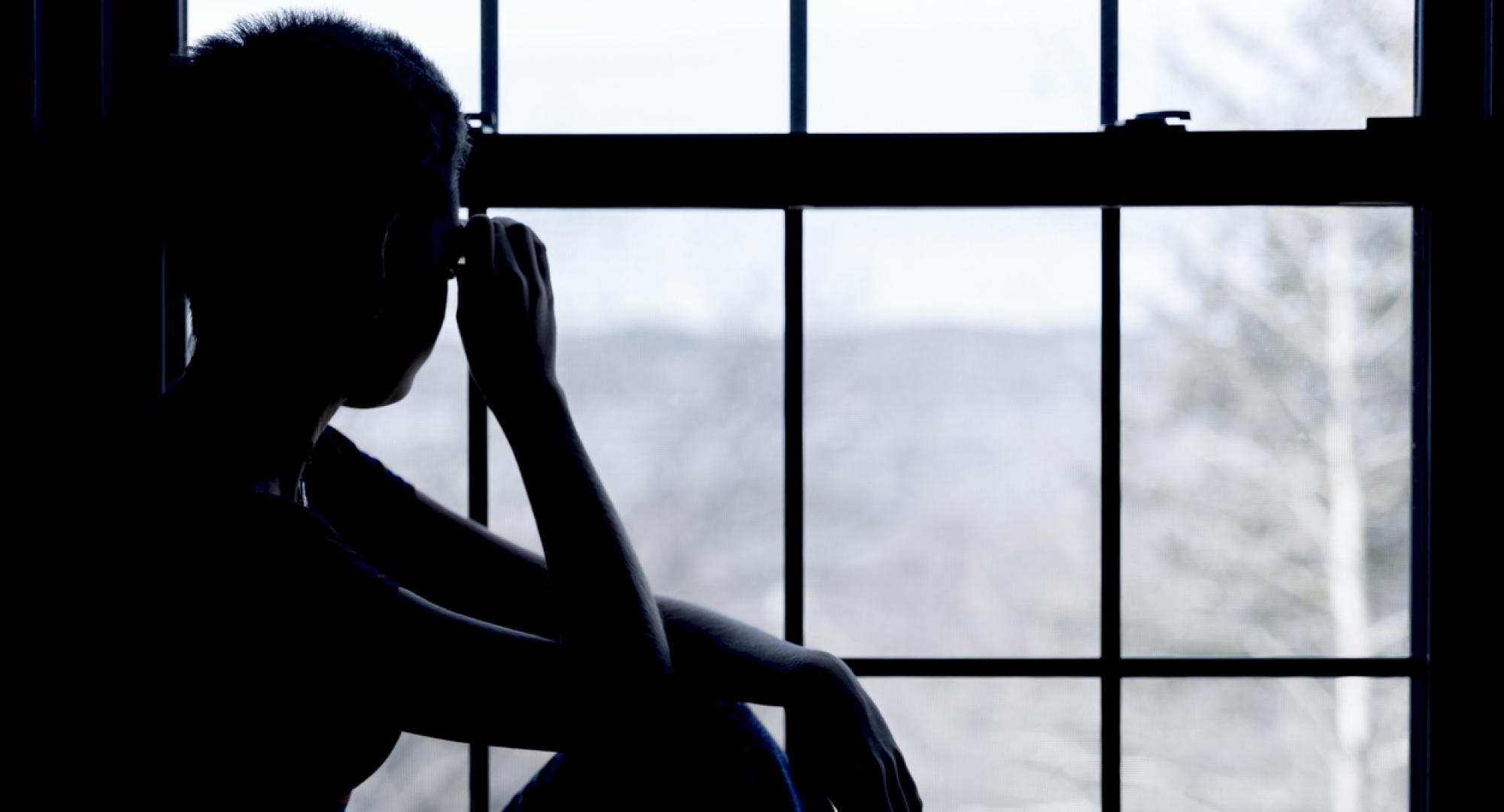 A homeless child looks out of the window of a hostel