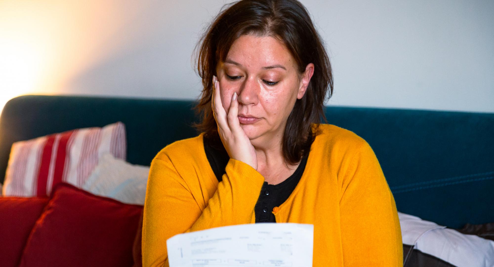 Woman looking sullenly at a bill