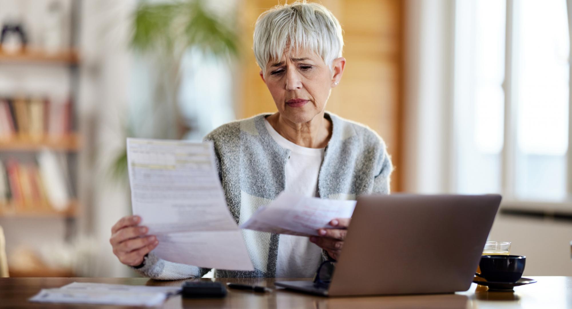 Older woman looking worried when looking at her bills