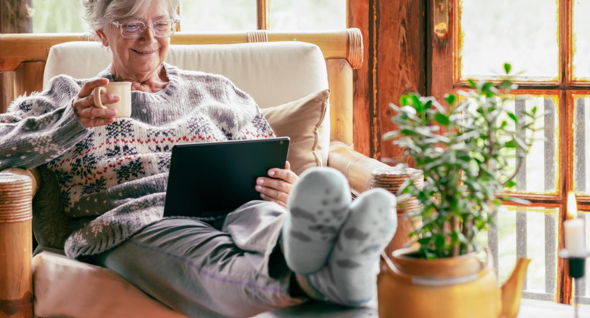Older lady sat at home using a tablet