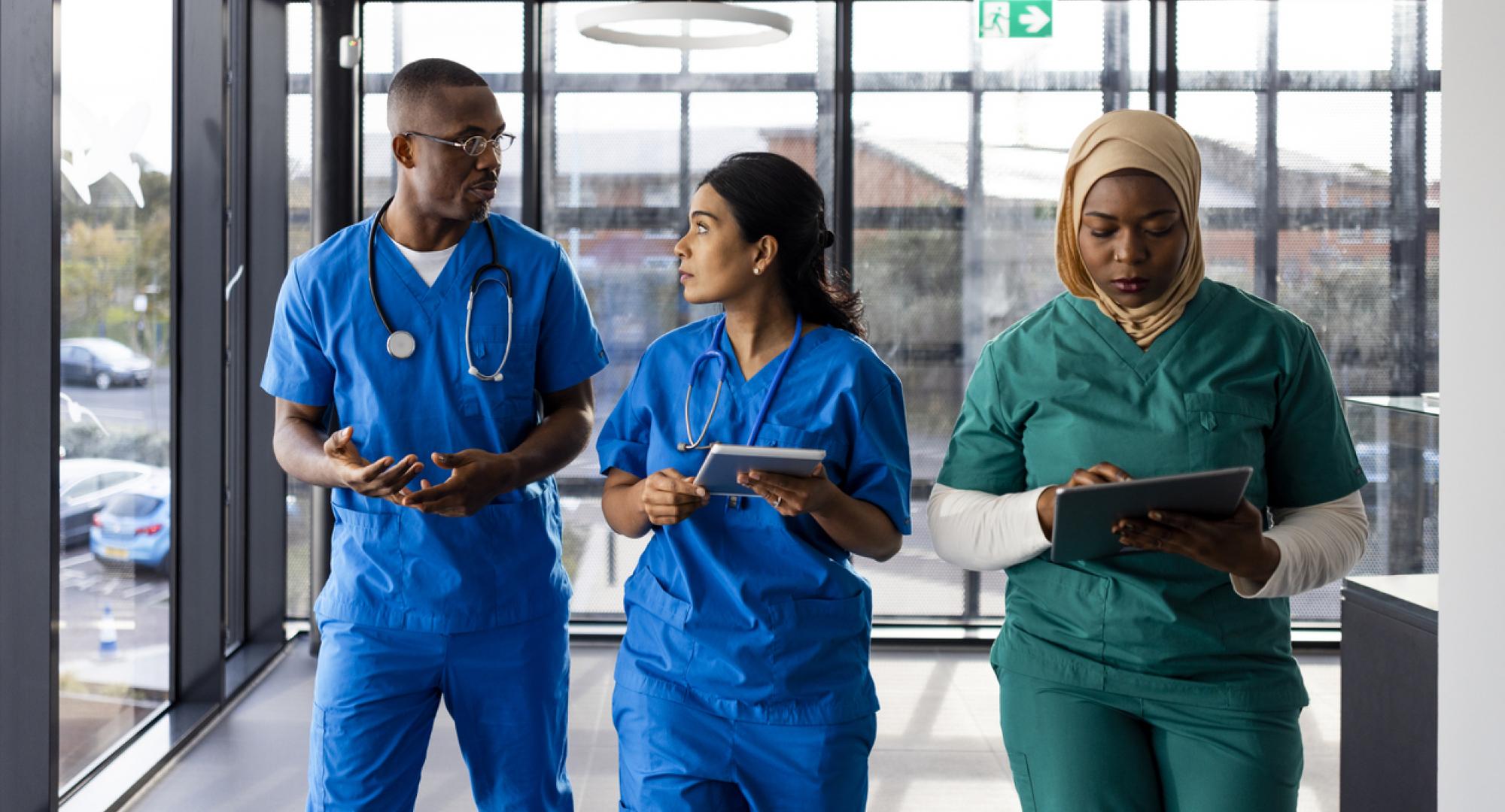 Three healthcare workers walking down a corridor in an English hospital