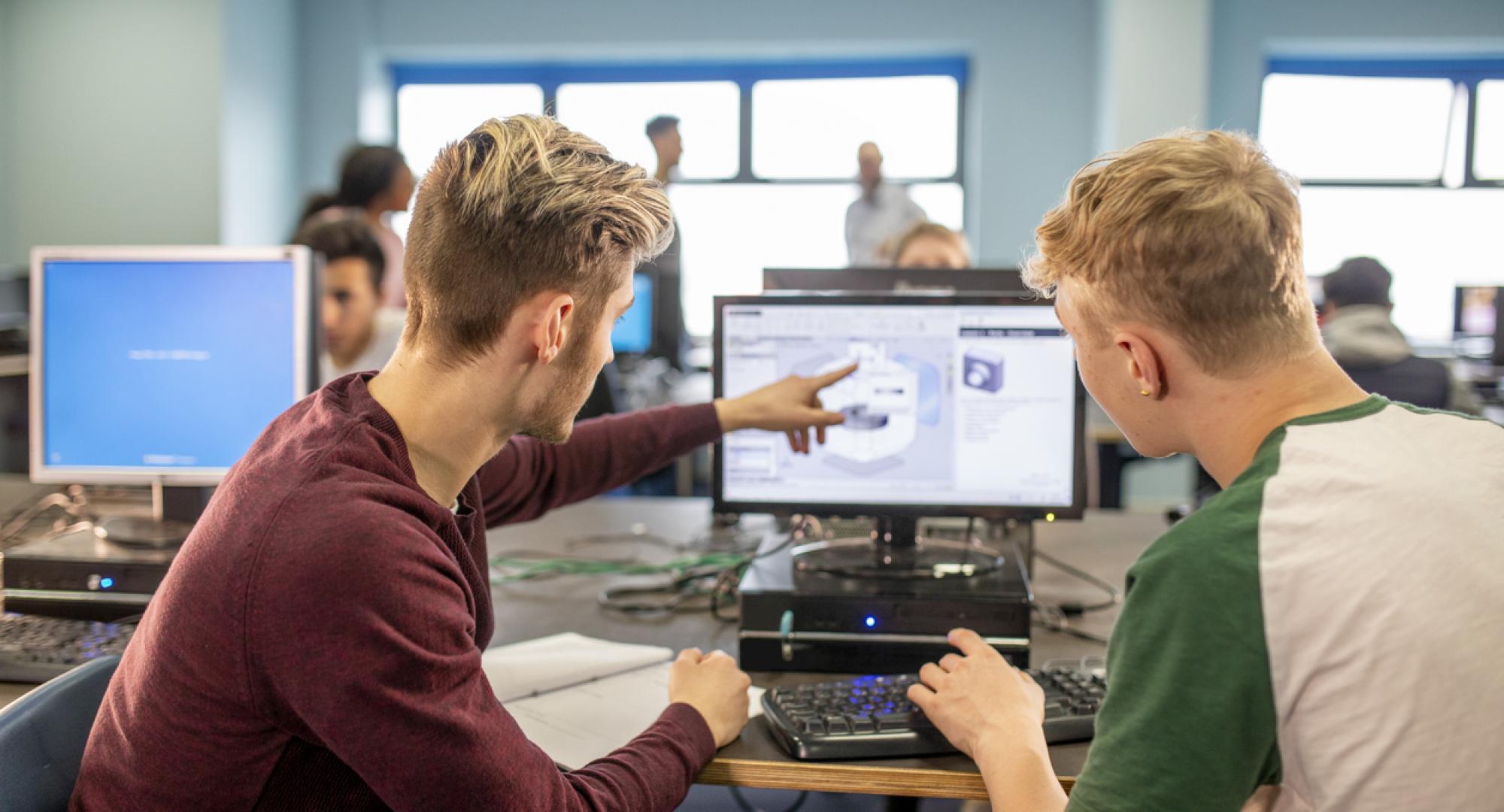 Two young men work together on a project on a computer
