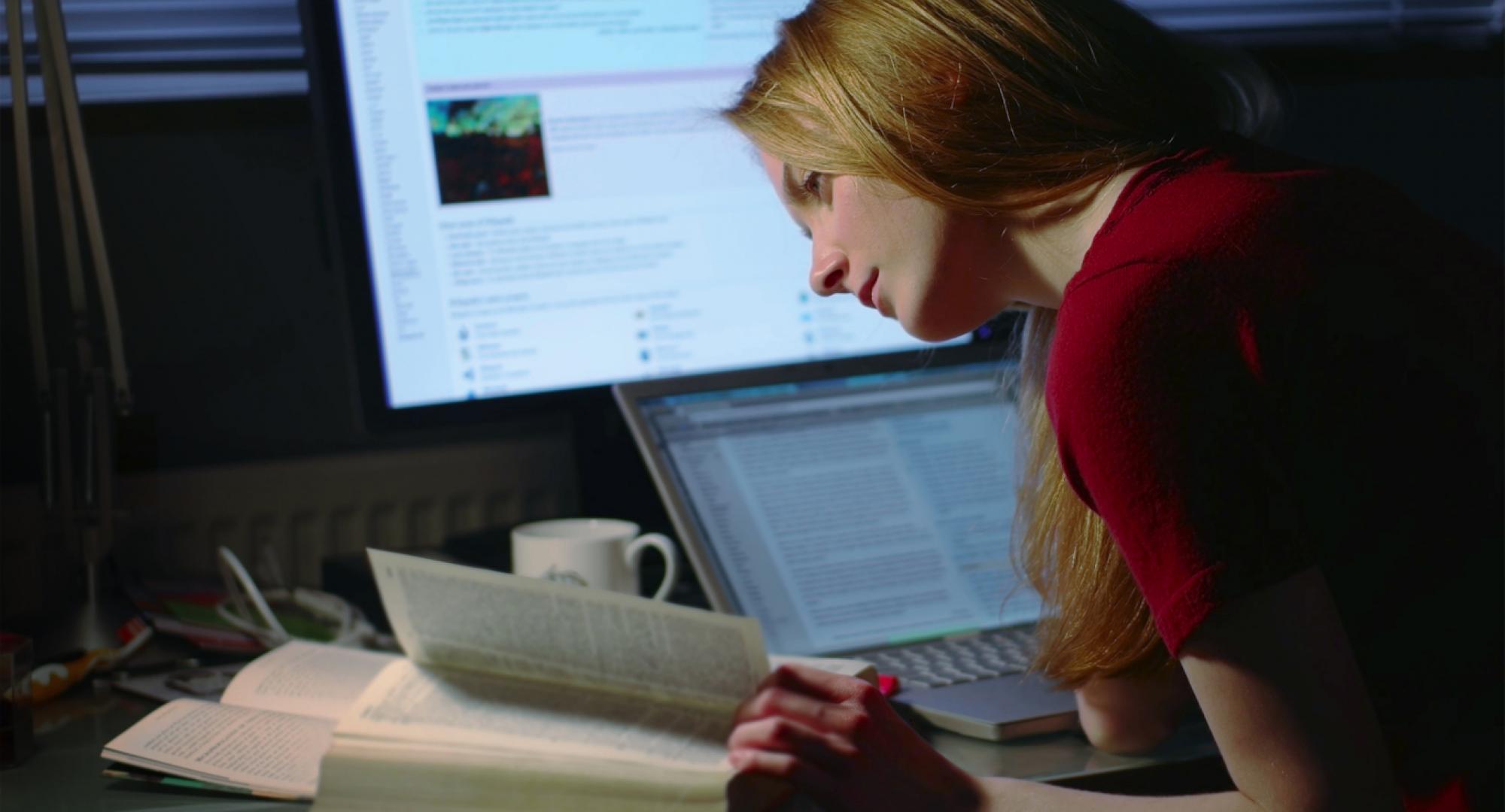 A girl studying/working at a desk with two computers