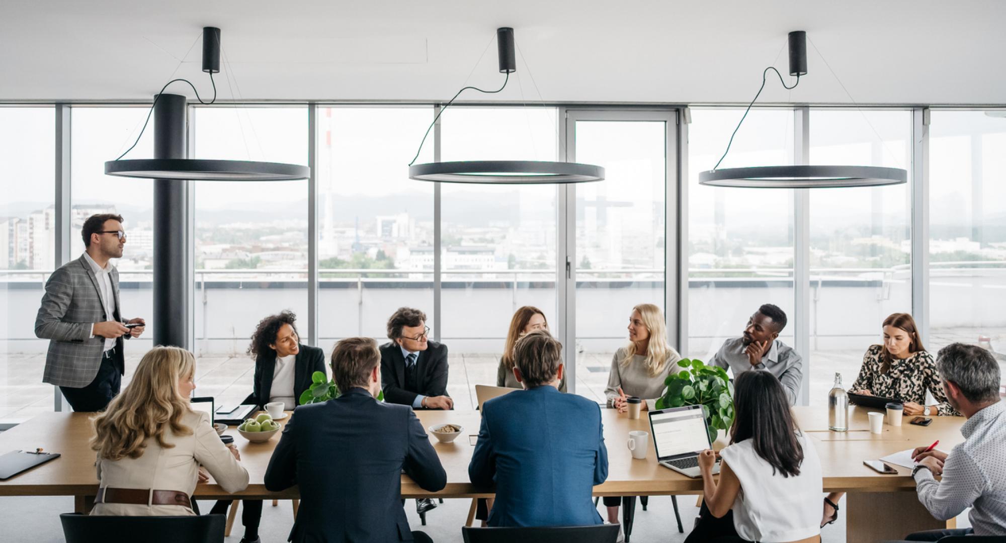 A photo of a business meeting in a modern office with large windows.