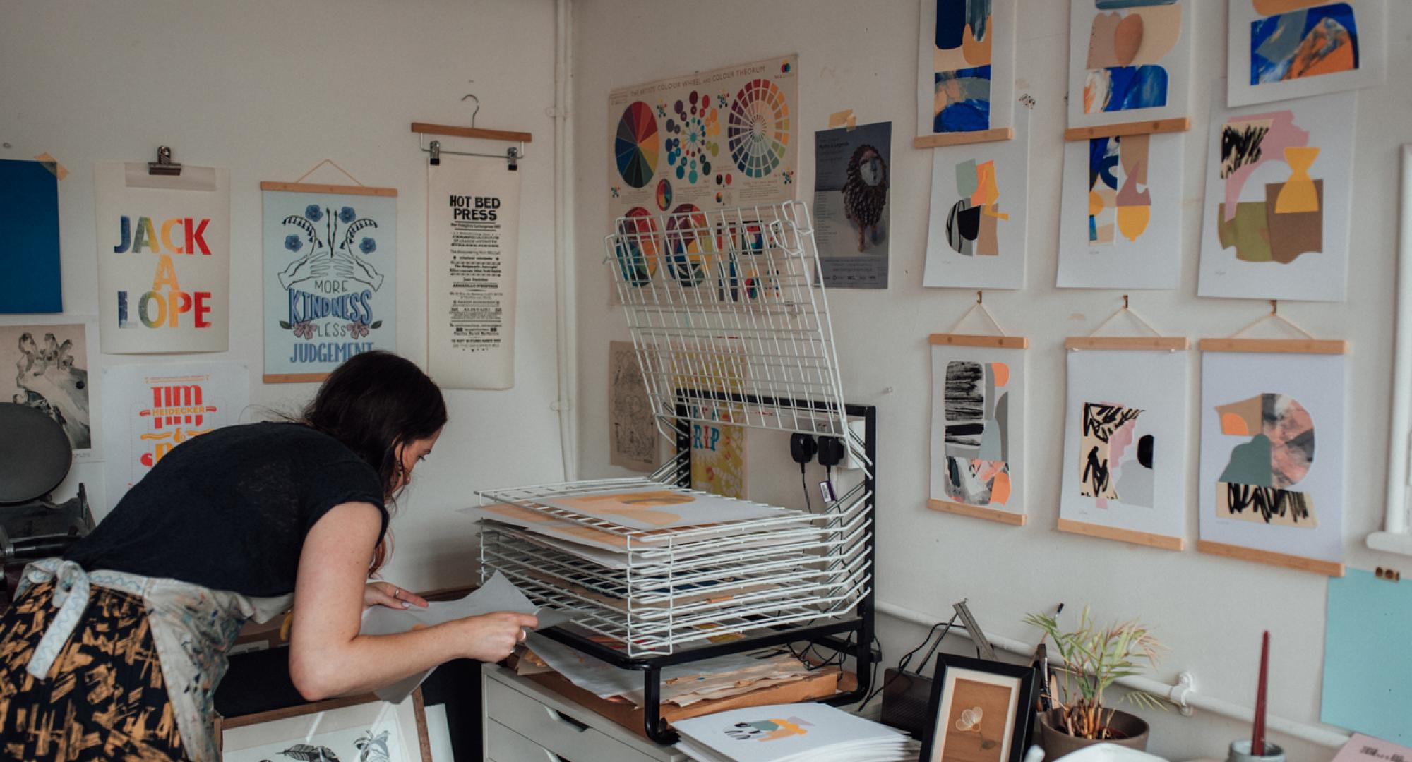 An artist laying prints to dry on a rack