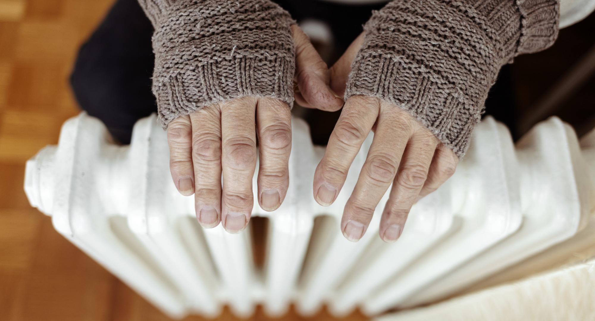 Woman warming hands up on a radiator