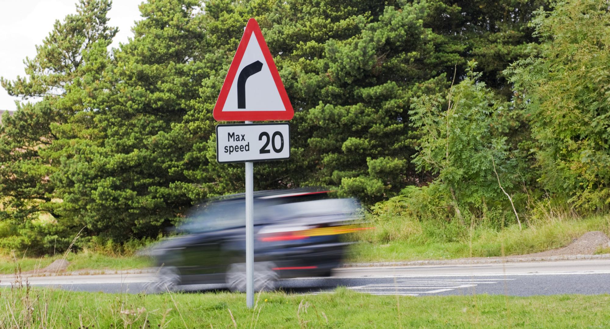 Speed limit sign as car drives past in the UK countryside