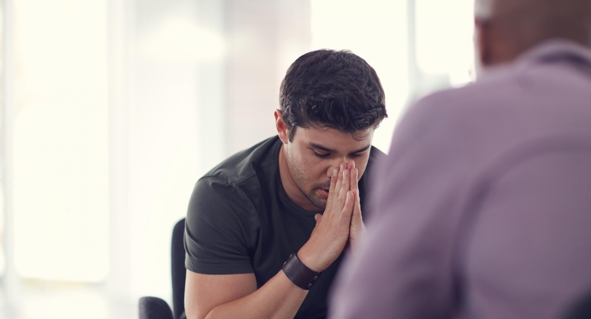 Shot of an unhappy young man talking with a colleague