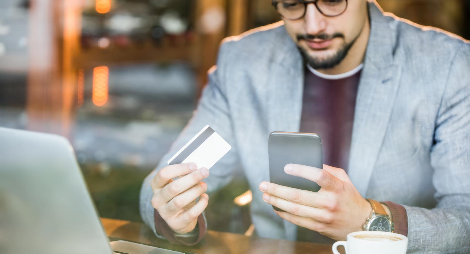 Young man using a credit card to invest online.