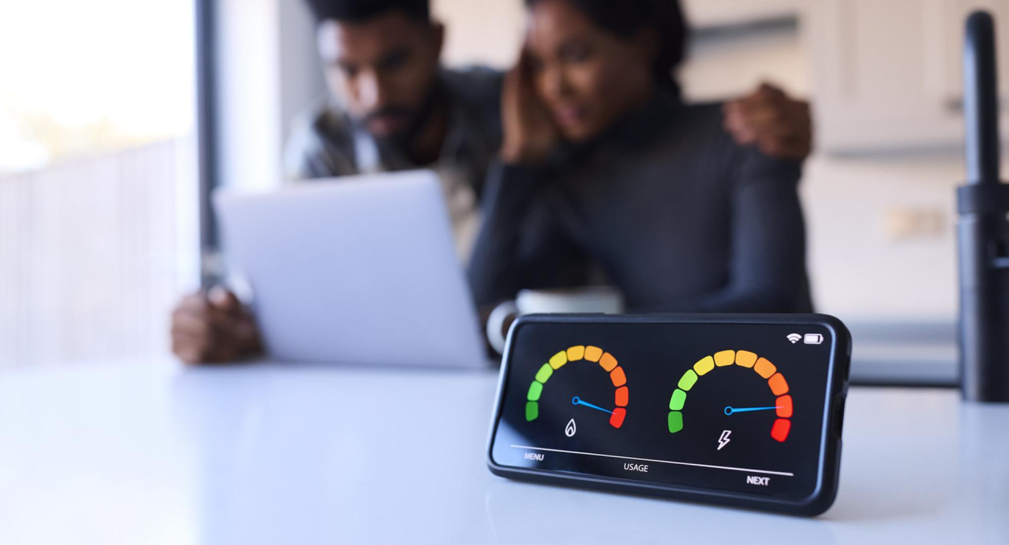 Couple looking anxious at laptop with smart energy meter in the foreground