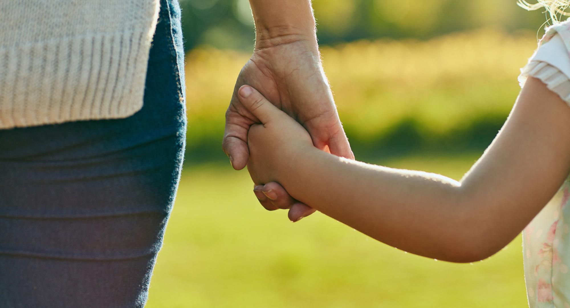 Woman and child holding hands on a sunny day