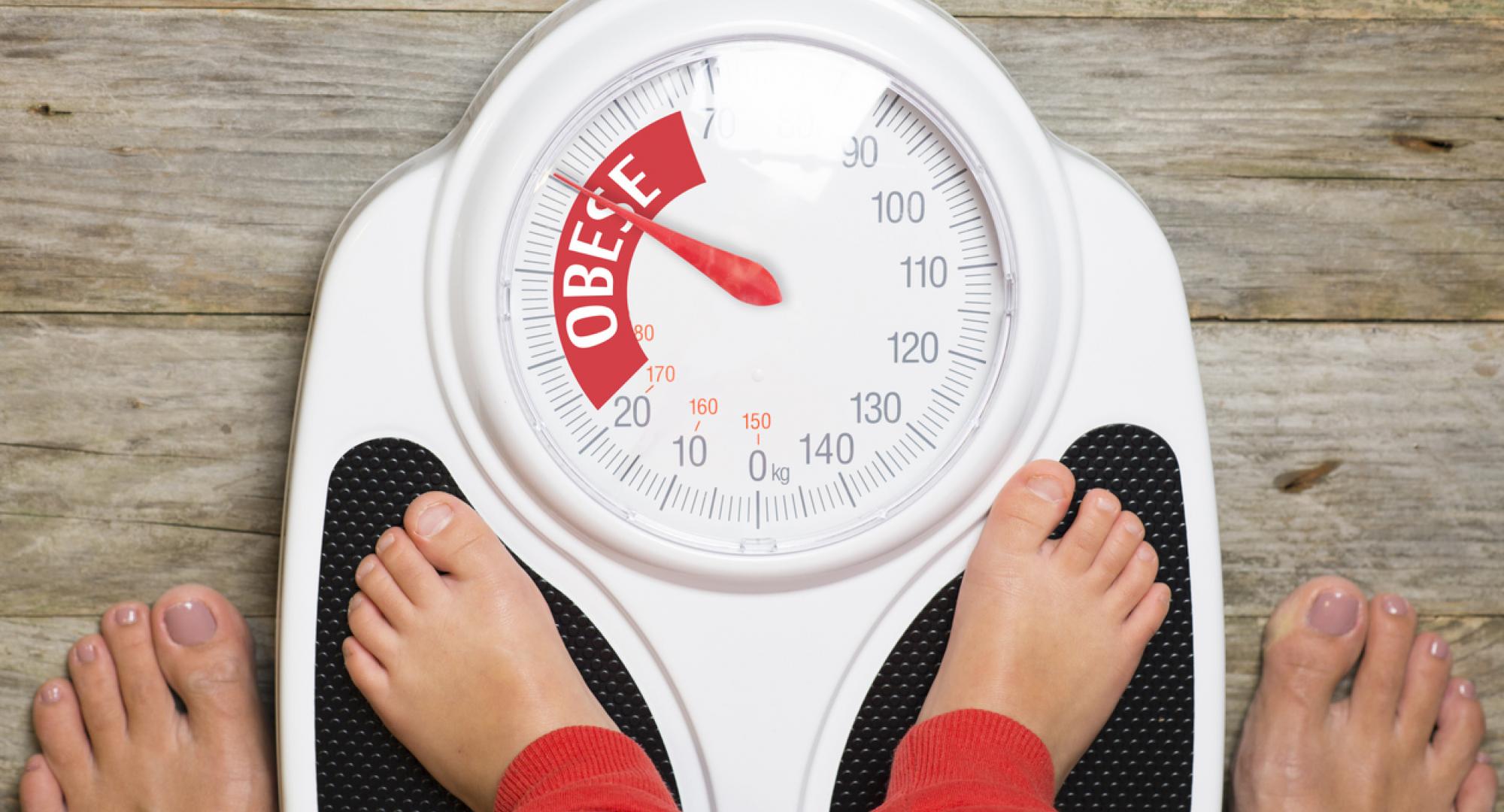 Child standing on scales pointing to 'obese'