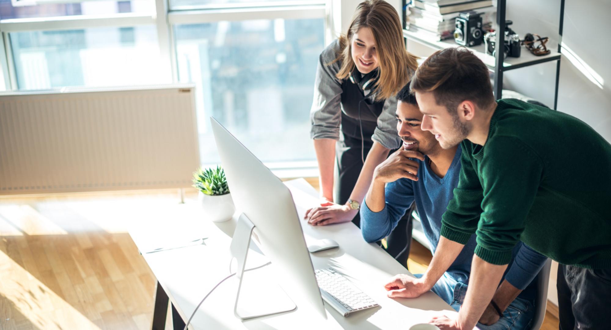 Three young people gathered round a computer