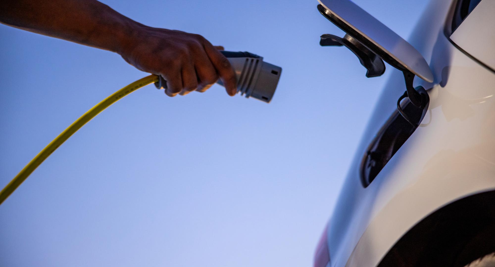 Person plugging an EV charger into an electric vehicle