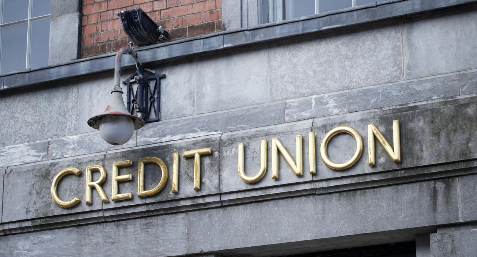 Sign of a credit union in gold writing on a stone wall