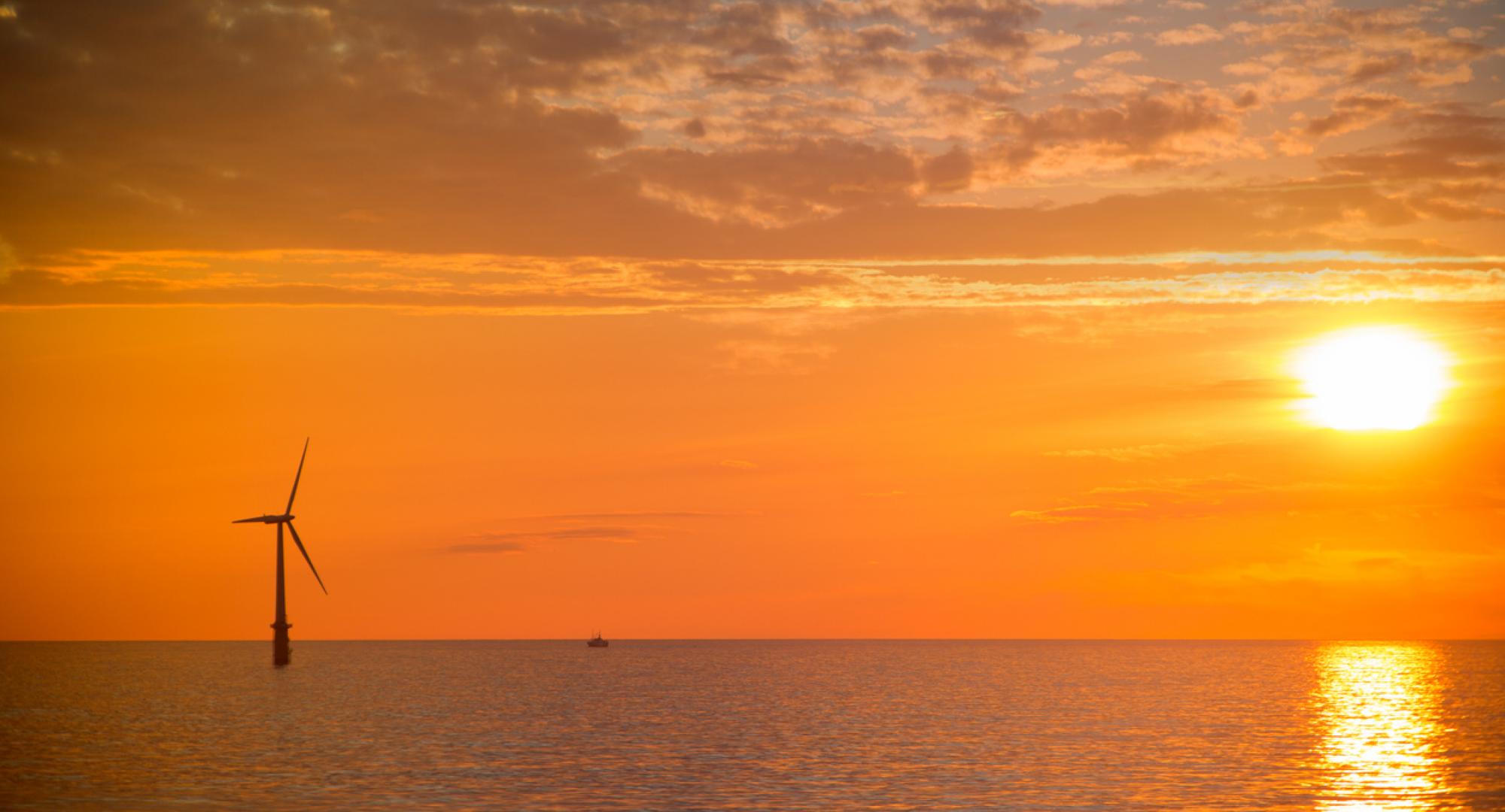 Sunset over the North Sea with a wind turbine in the distance