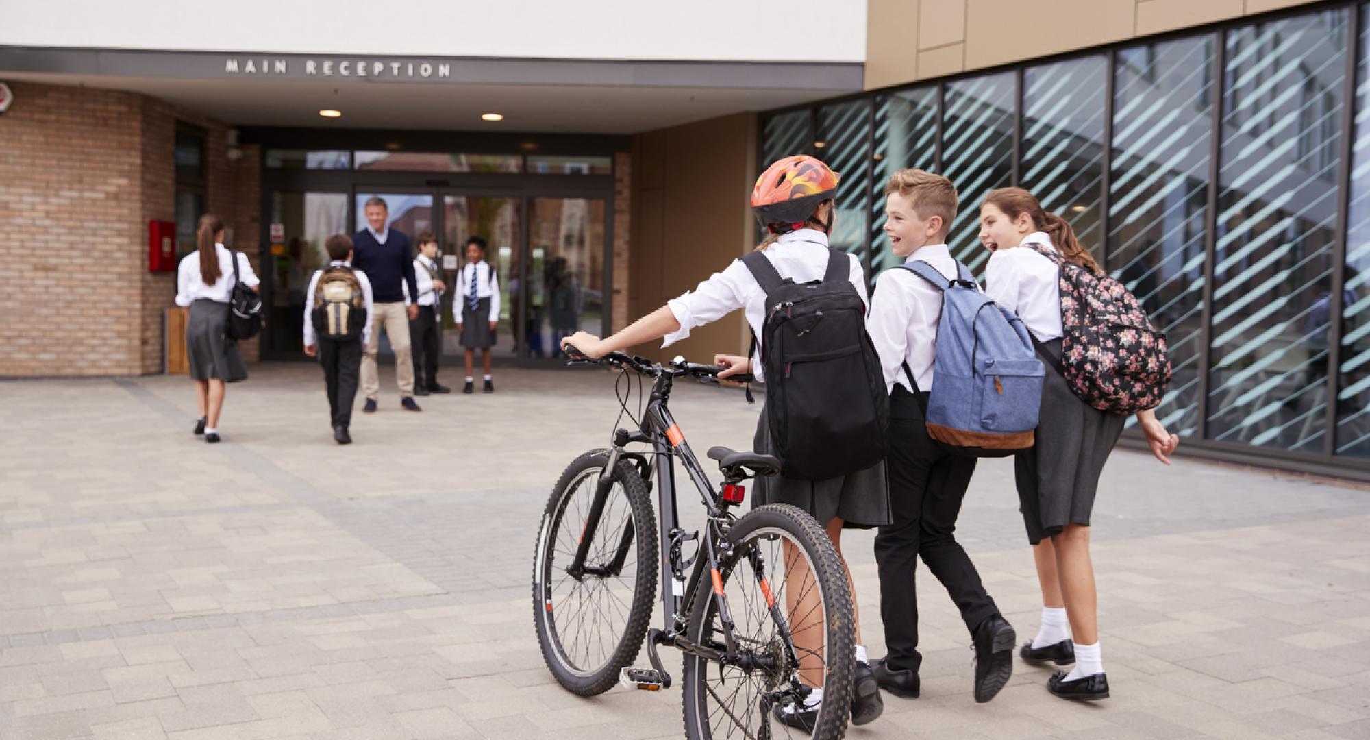 Student walking into school with a bike