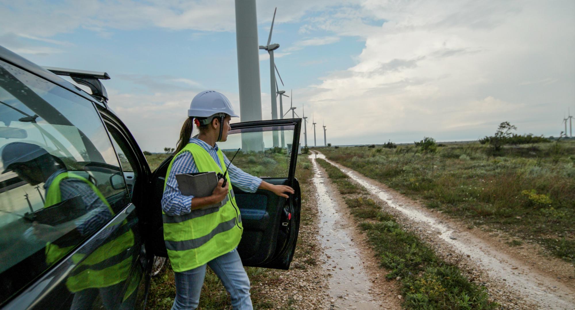 Woman getting out of a car at a group of wind turbines