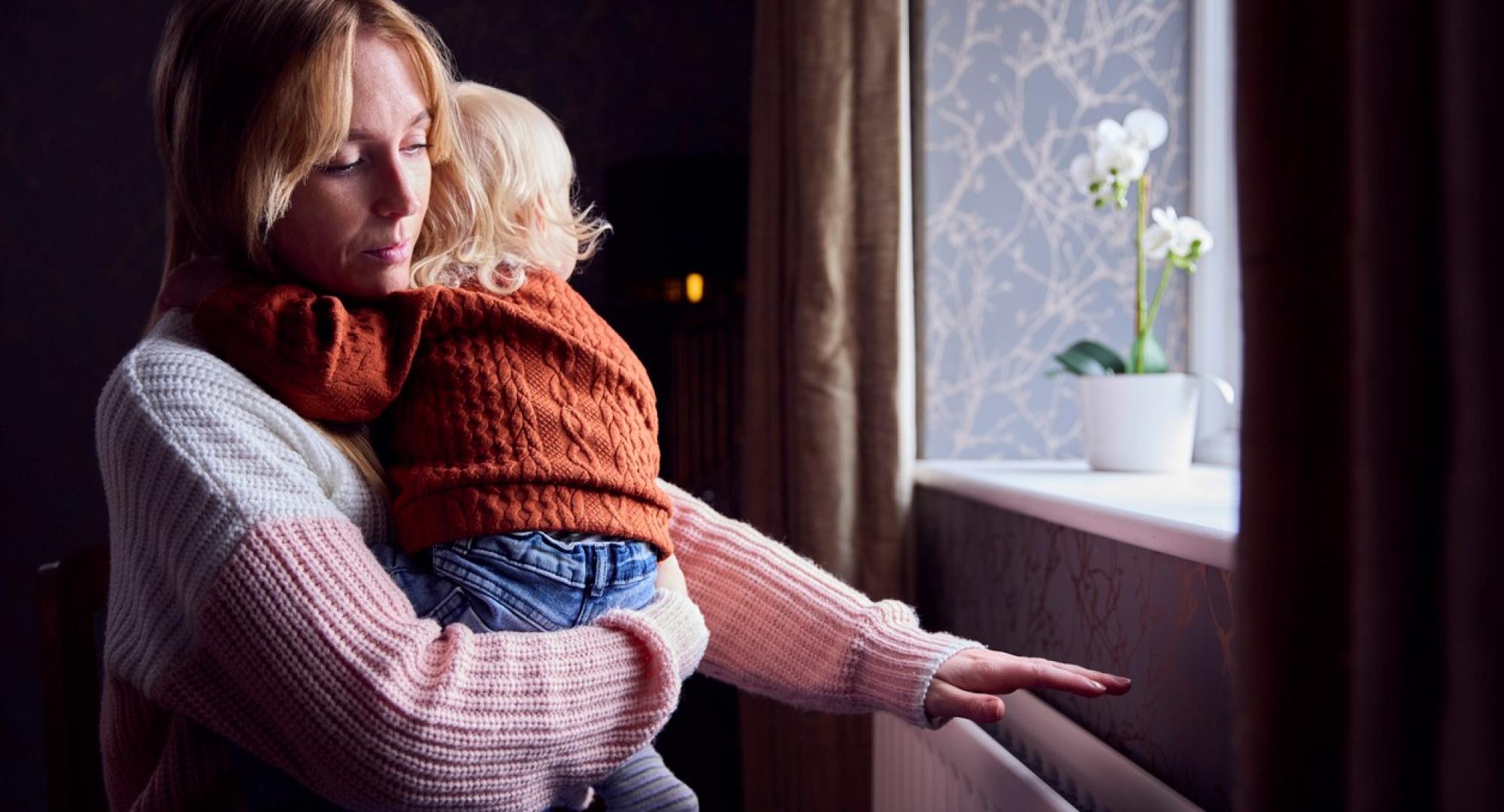 Woman looking out of a window with a child in her arms