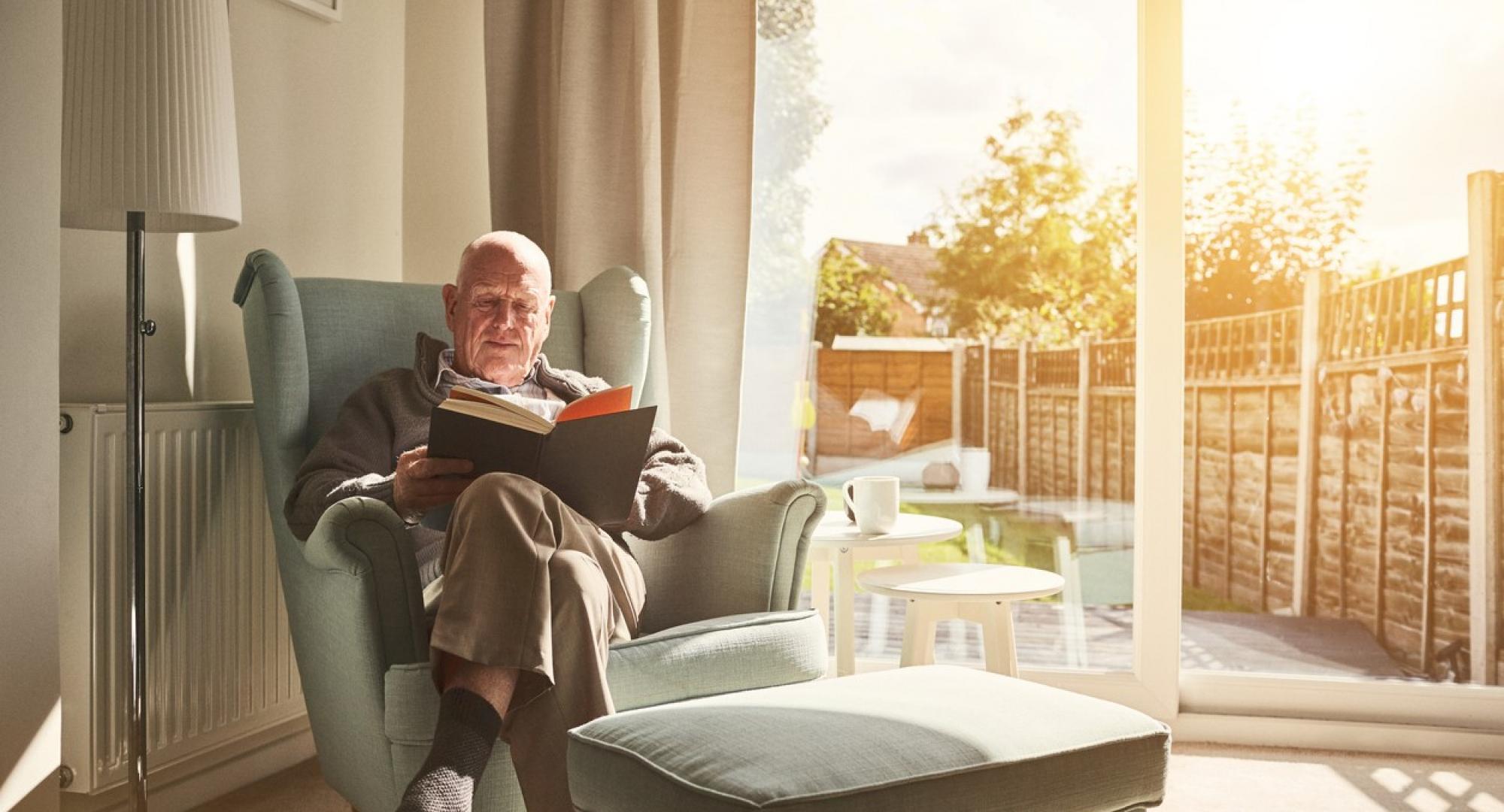 Old man reading in his home