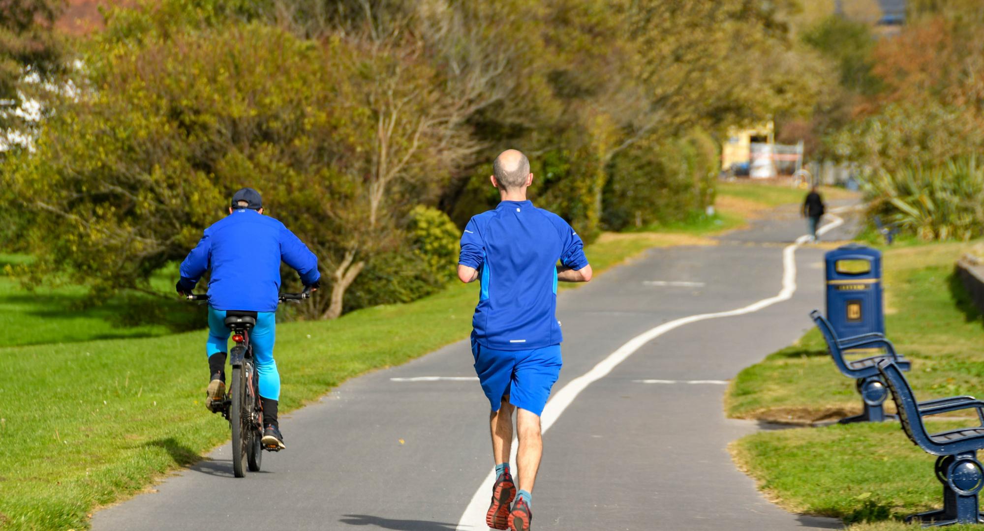 Person jogging behind a cyclist on the Wales National Coastal Path