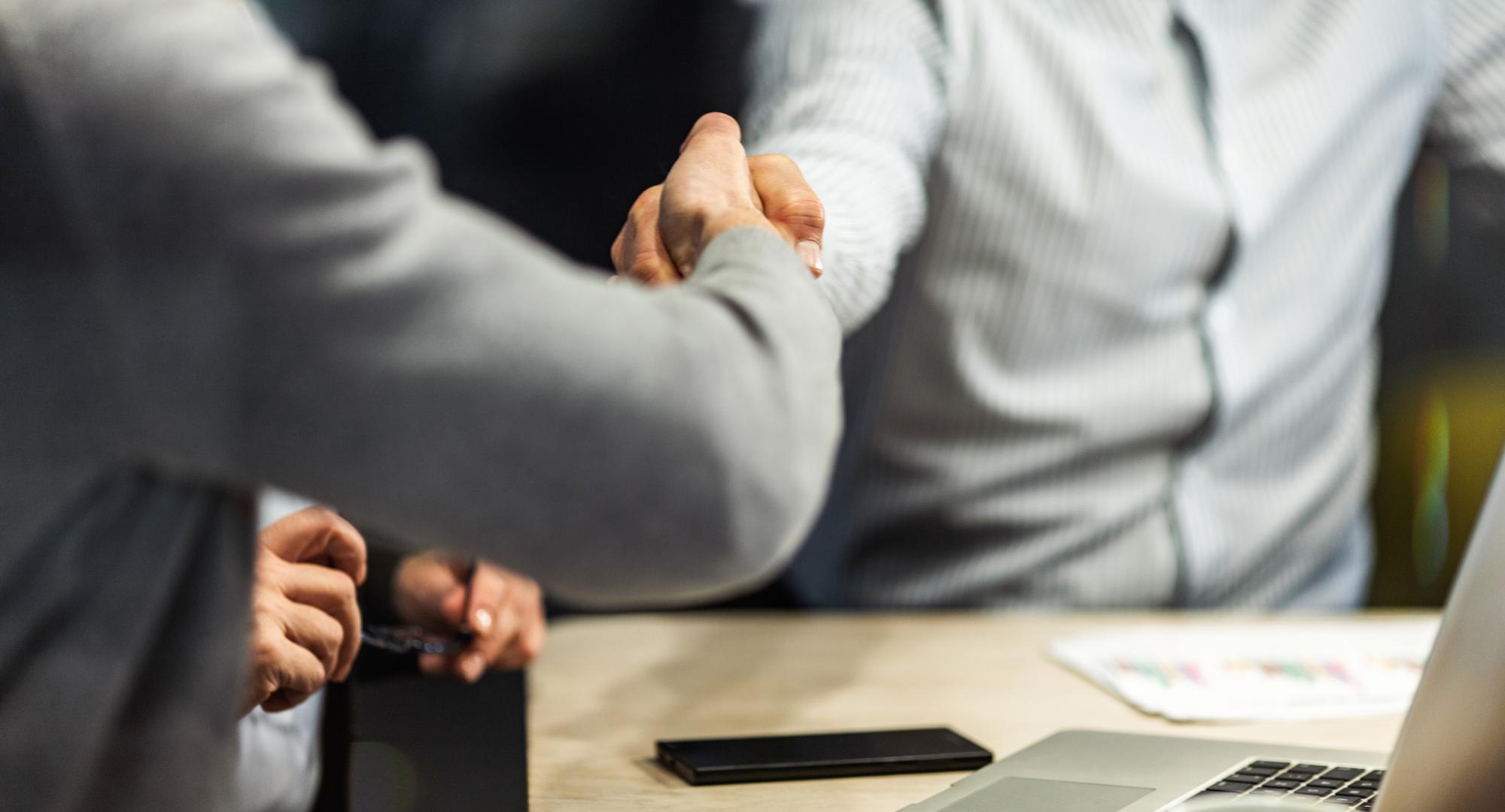 Two people shaking hands over a business agreement