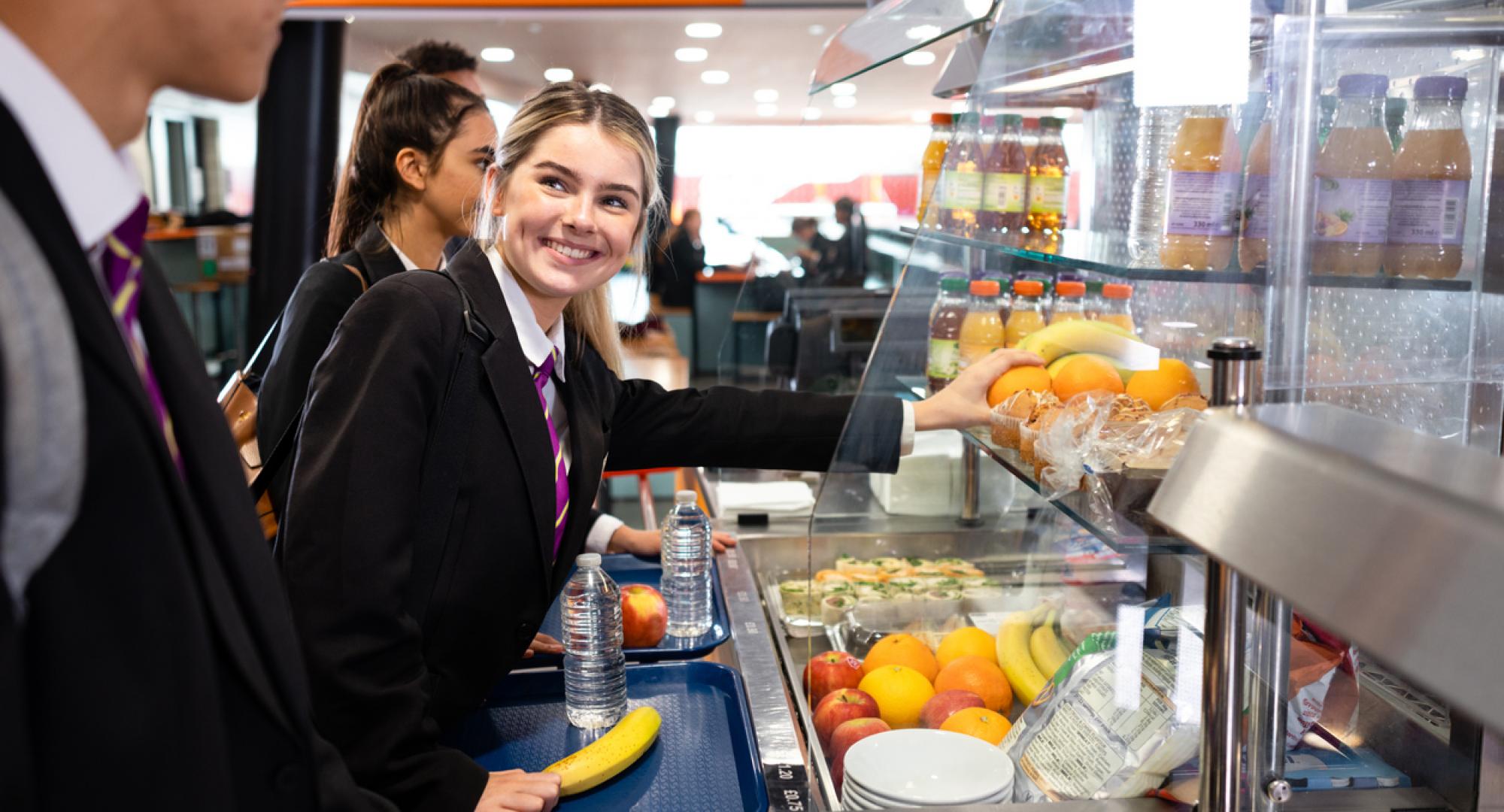 Schoolgirl smiling in the queue for lunch at school