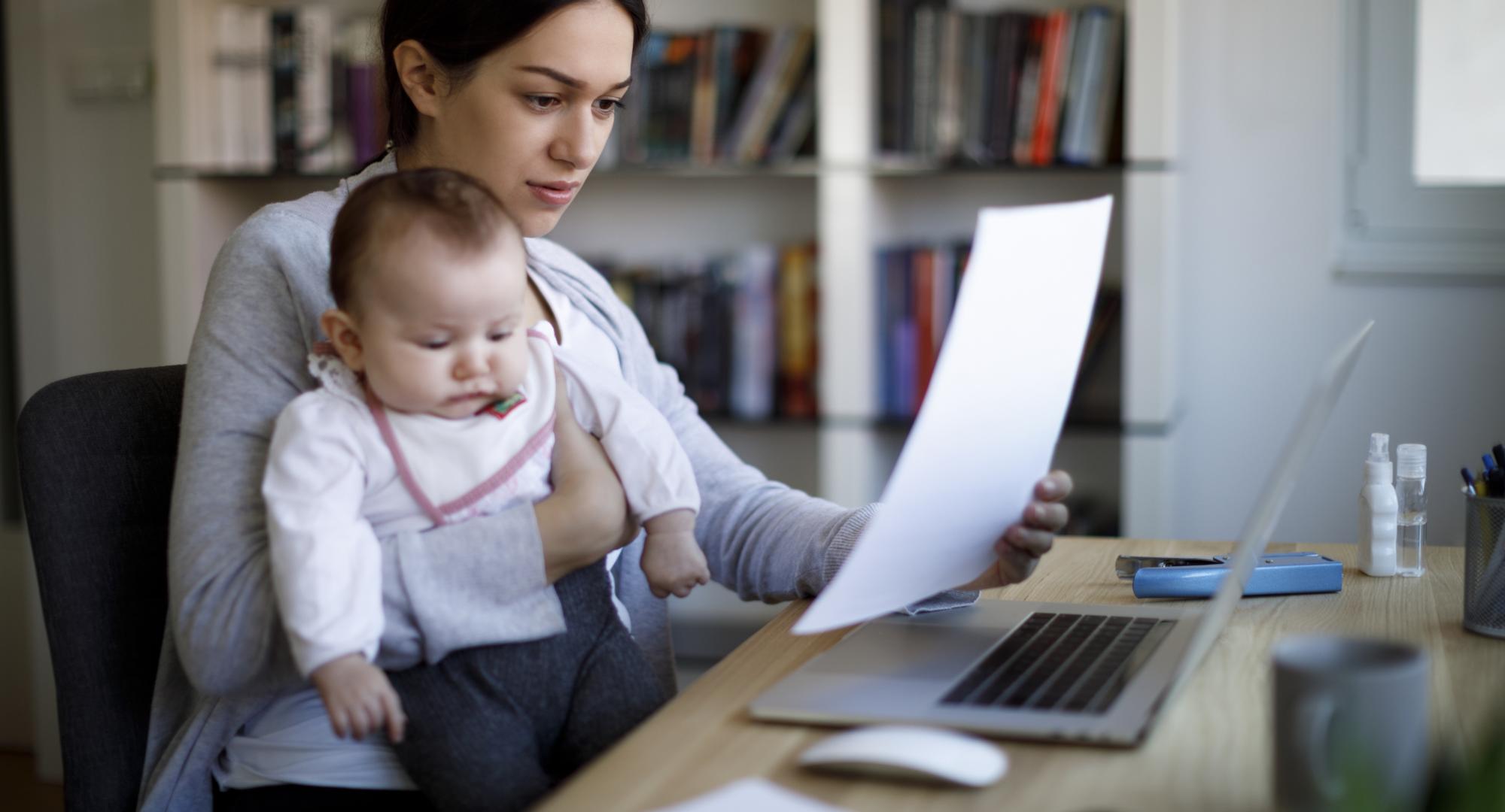 Woman holding baby and looking at a bill