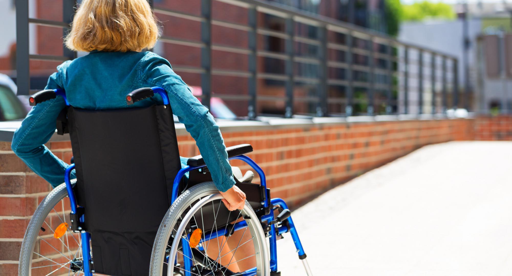 Woman sat in a wheelchair, going up a ramp