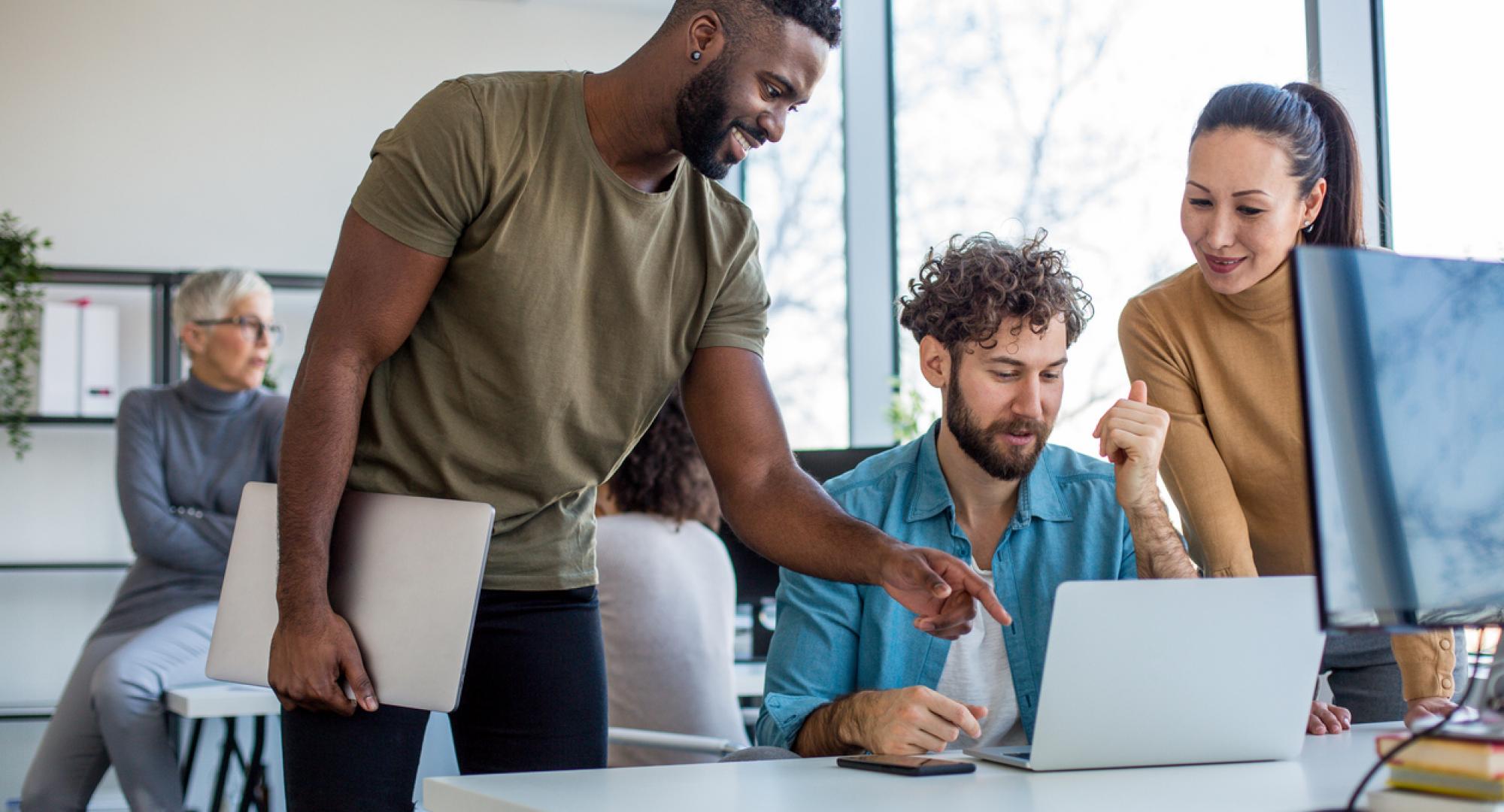 A team of creative professionals looking at the lap top and brainstorming ideas