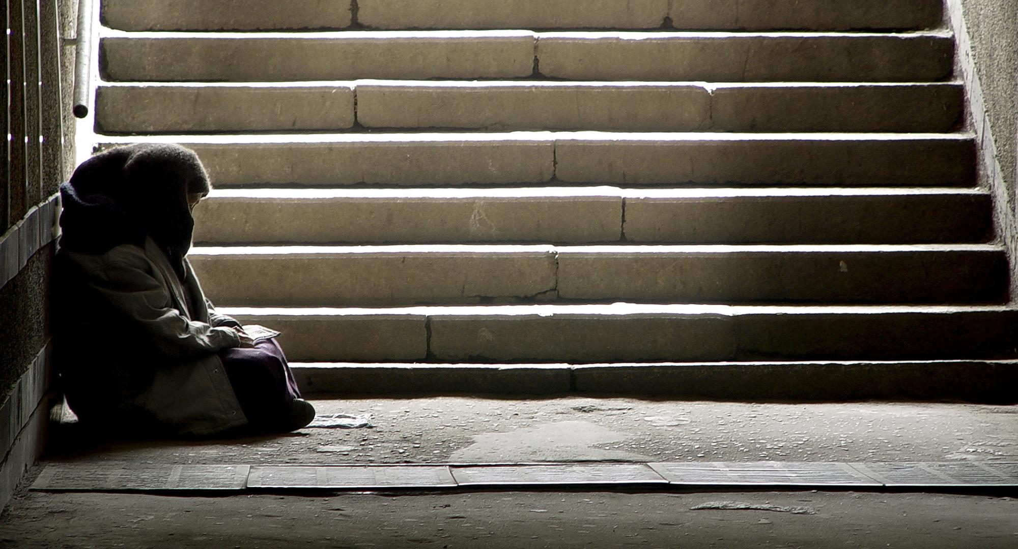 Homeless woman sitting on the floor by some steps