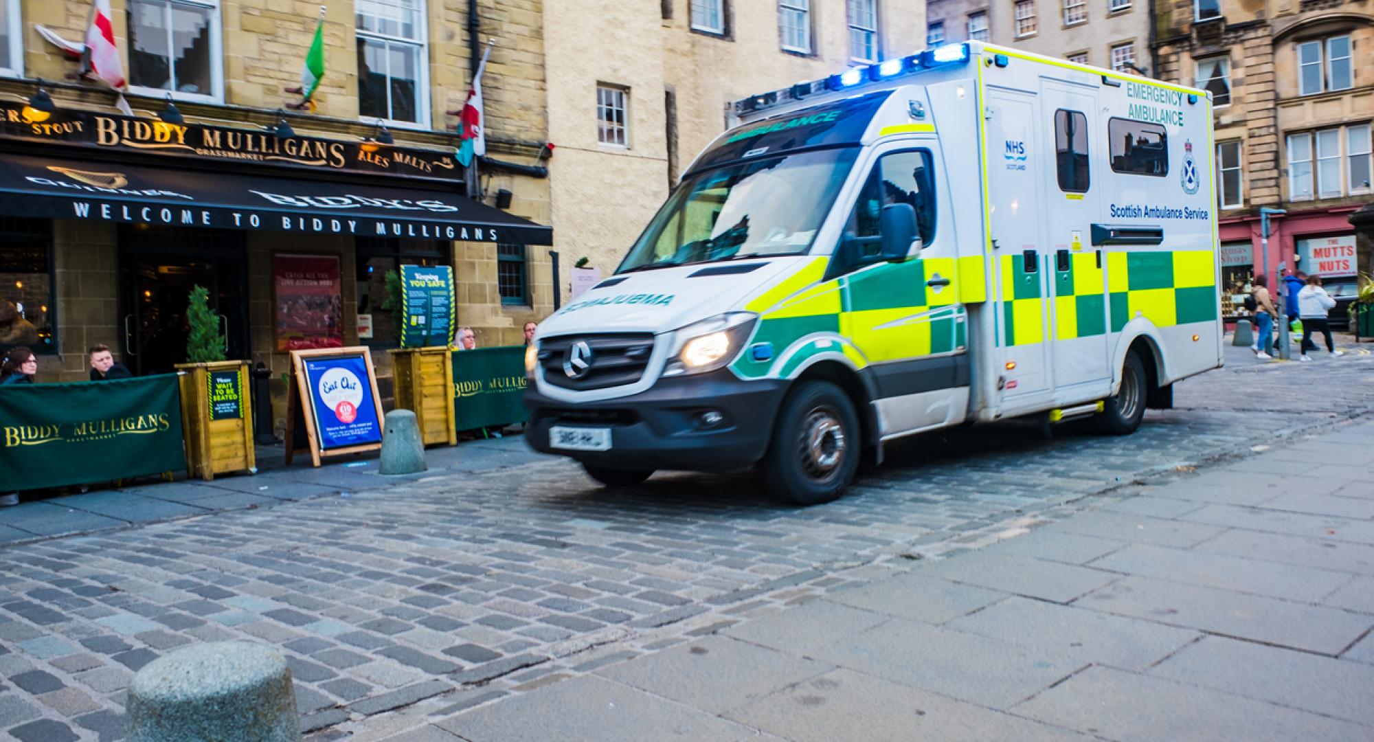 Emergency Ambulance driving through Grassmarket in Edinburgh