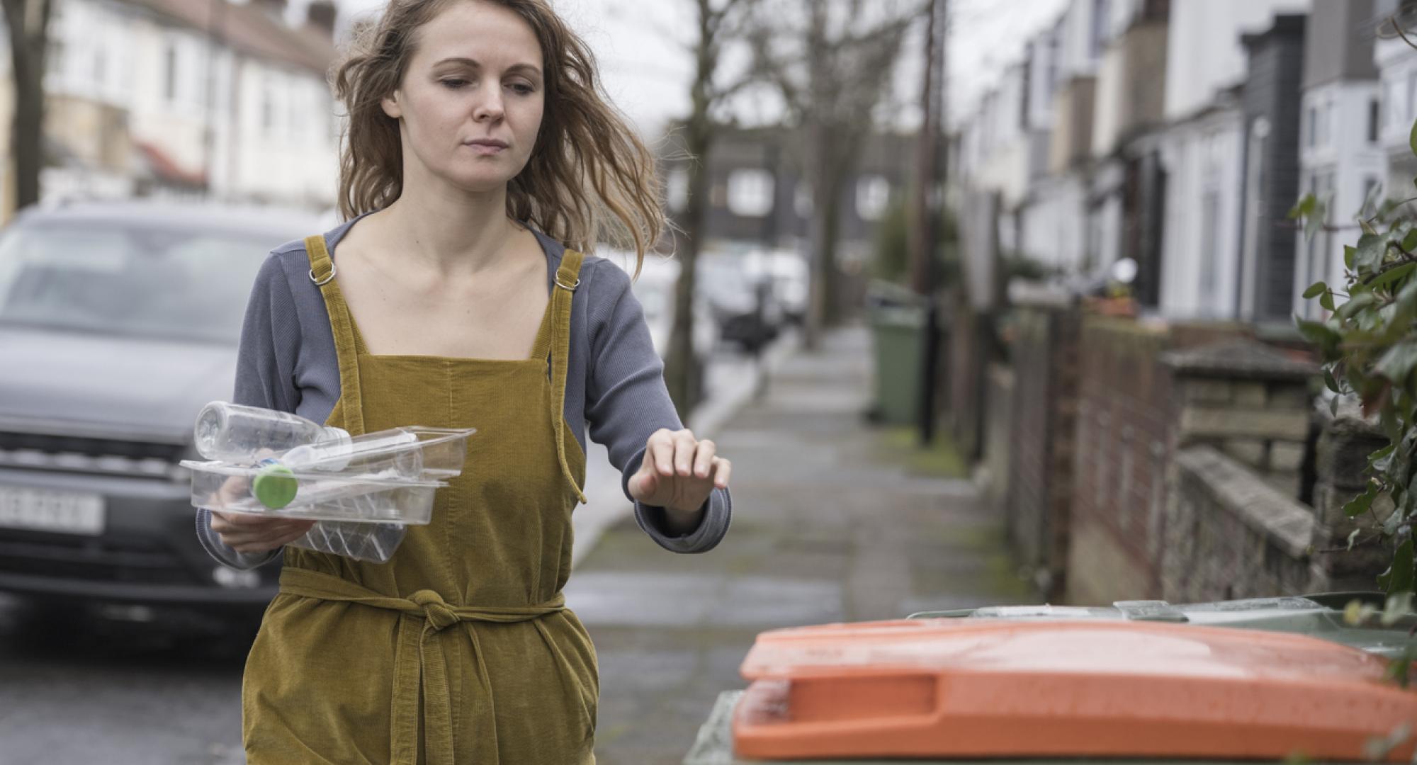 Mid adult British woman recycling plastic containers