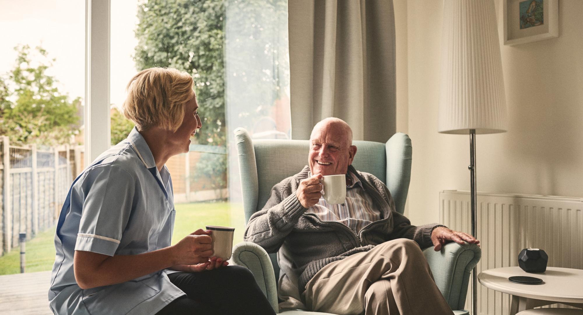 Relaxed senior man and female nurse having coffee