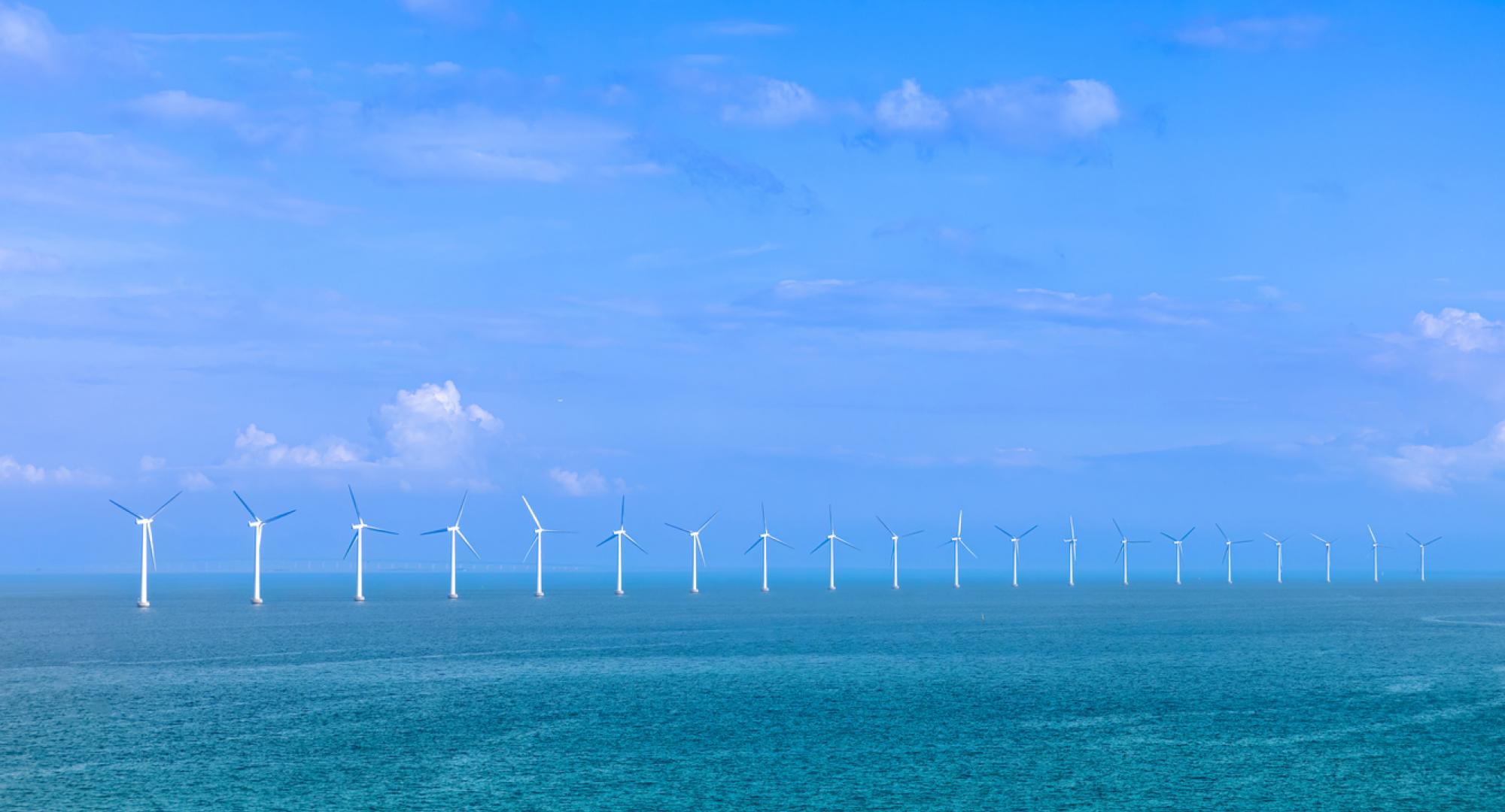 Renewable energy wind power plant and wind turbines along sea shoreline