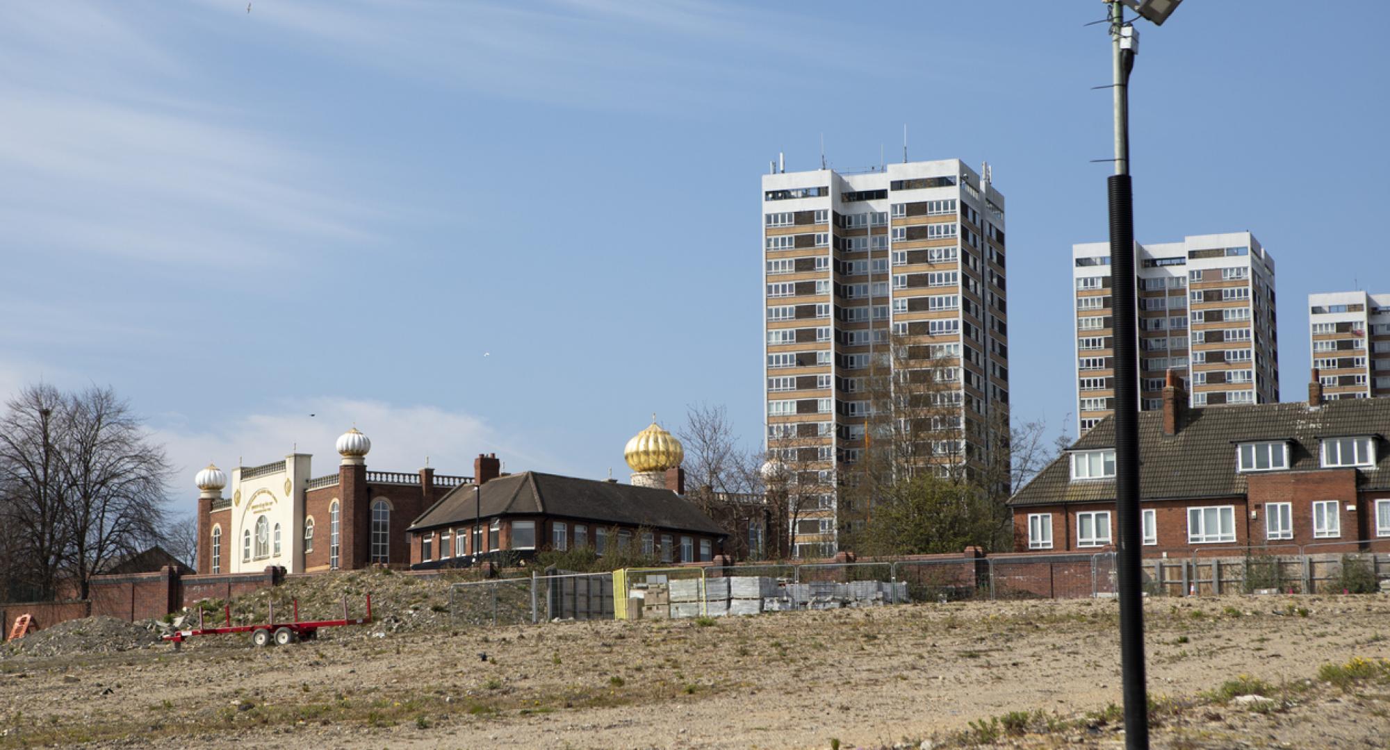 housing against a clear sky with barren land ready for development in the foregound