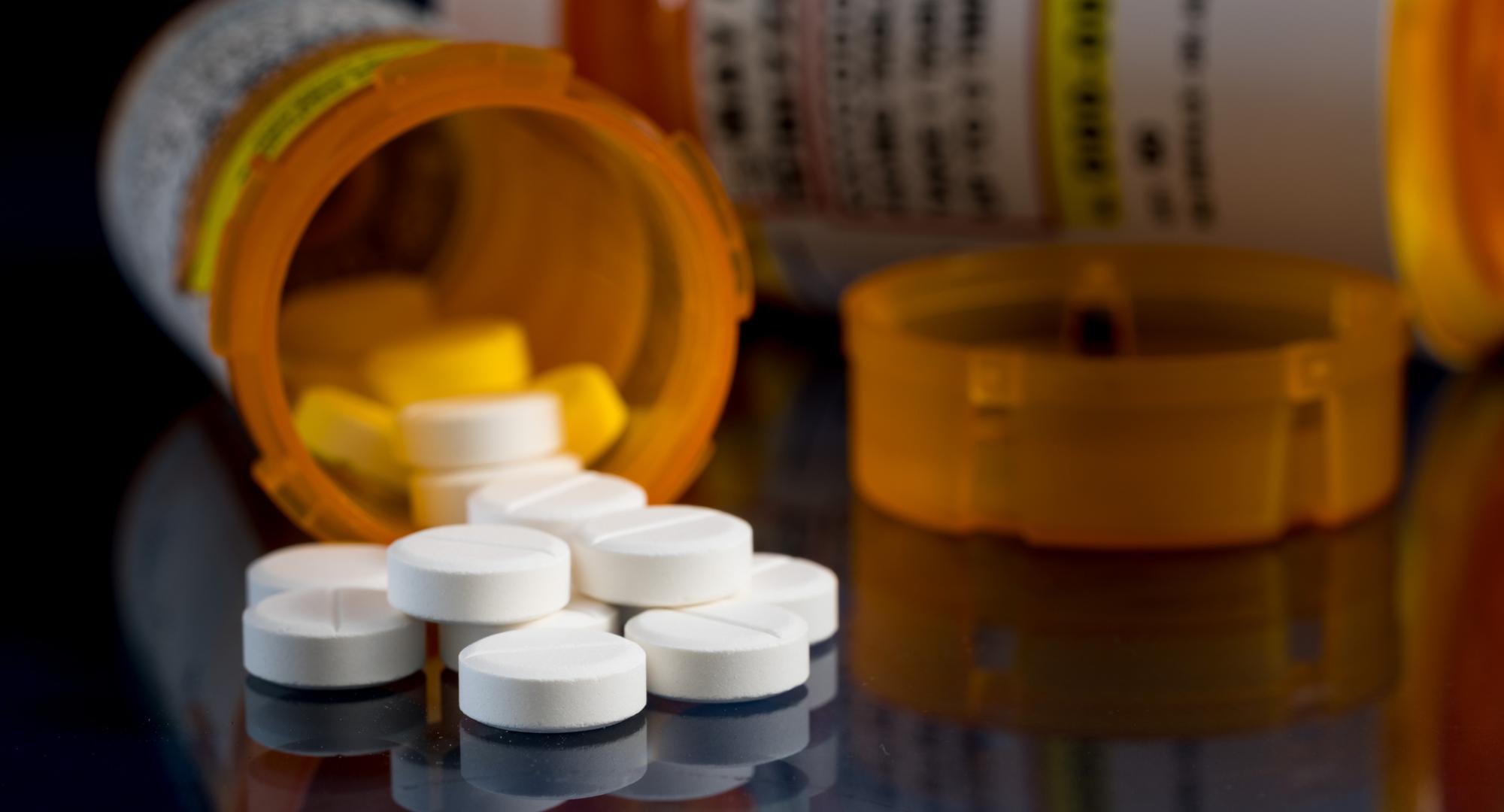 Prescription bottle for Oxycodone tablets and pills on glass table with reflections