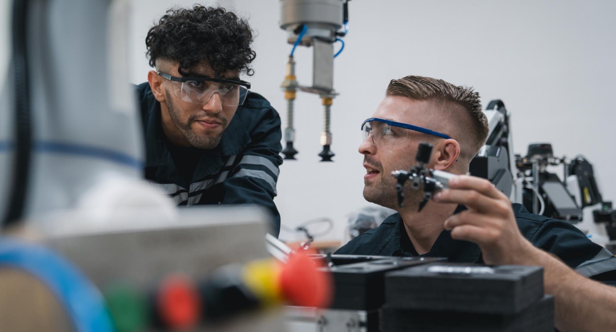 Student engineer Assembling Robotic Arm with computer in Technology Workshop